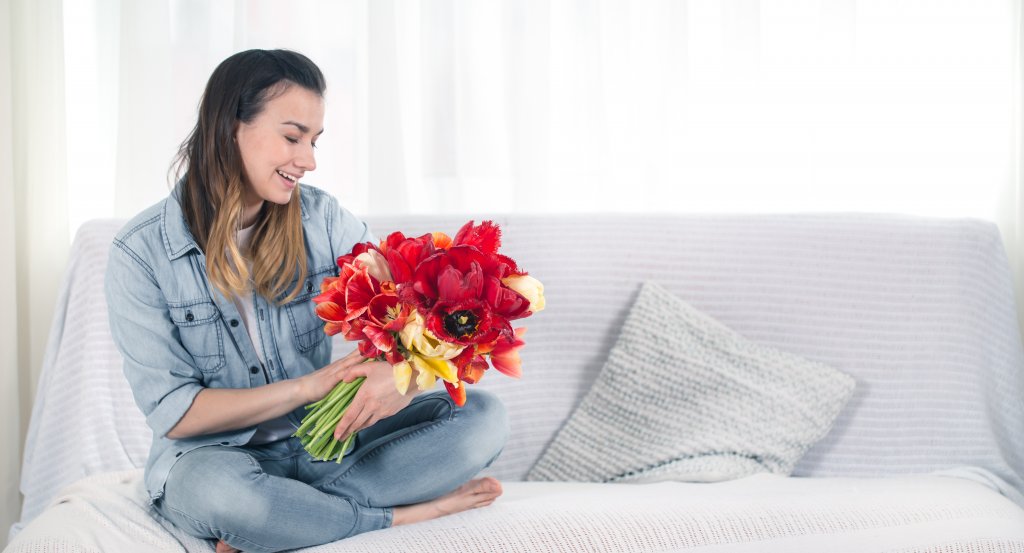 a-young-girl-with-a-large-bouquet-of-tulips-sitting-on-the-couch-in-the-living-room.jpg