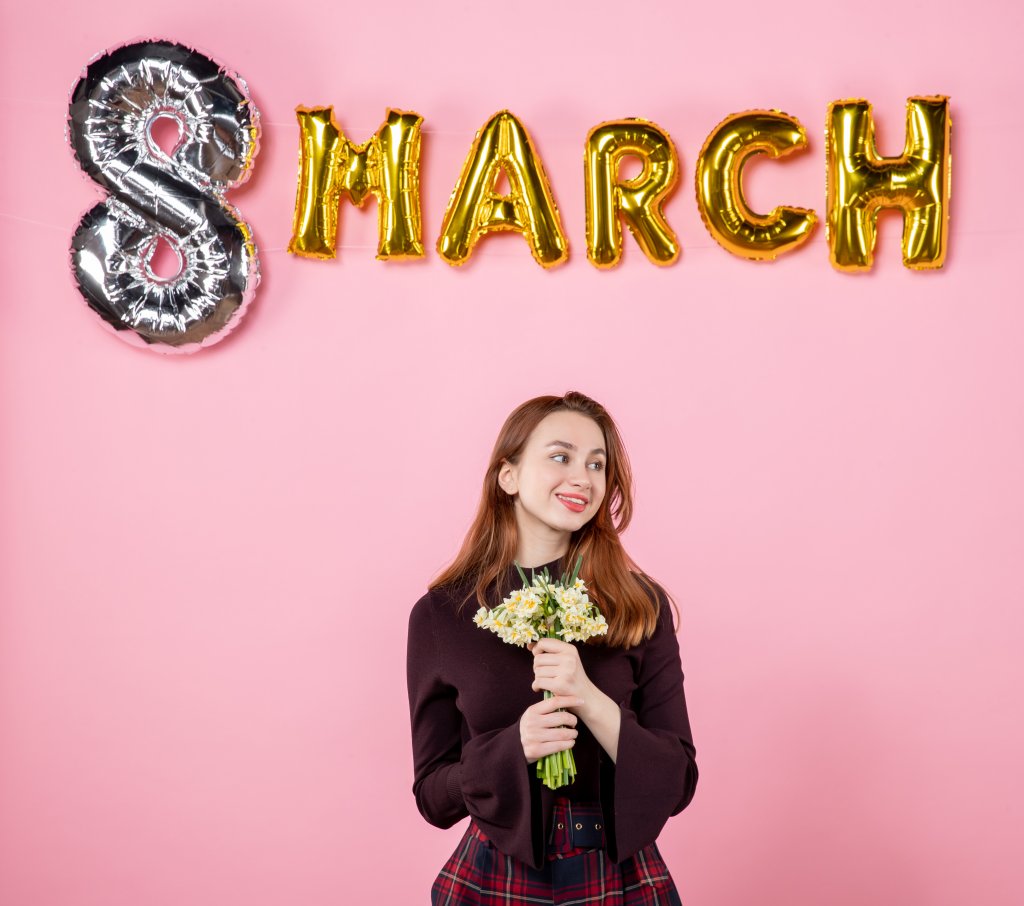 front-view-young-female-with-flowers-in-her-hands-and-march-decoration-on-pink-background-party-womens-day-march-marriage-sensual-present-equality.jpg